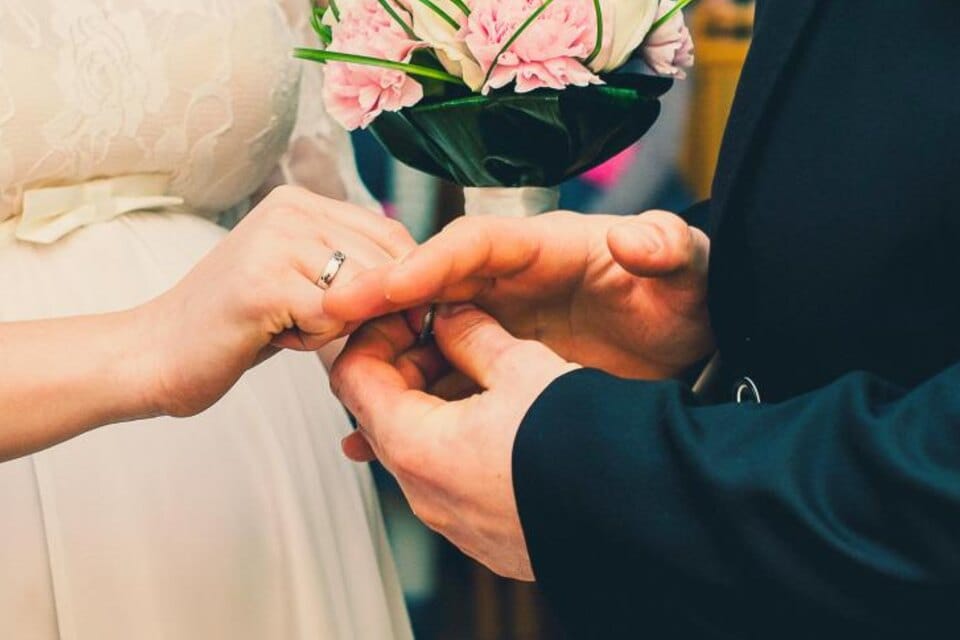A diamond engagement ring on the hand held among flowers