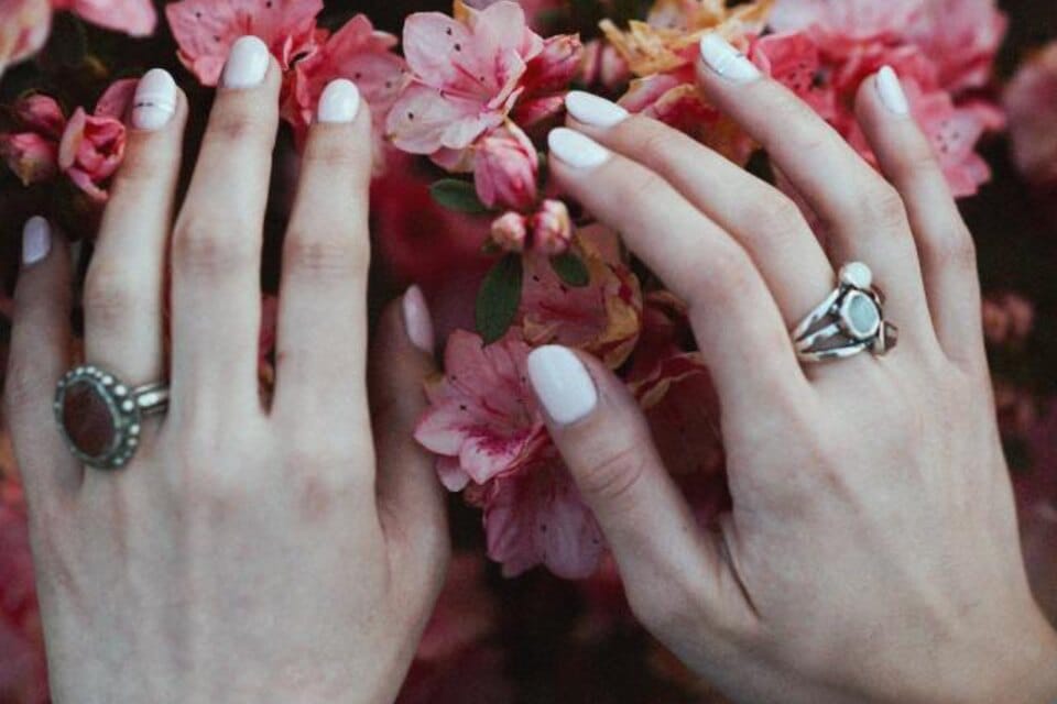 A hand wearing a diamond engagement ring resting on flowers