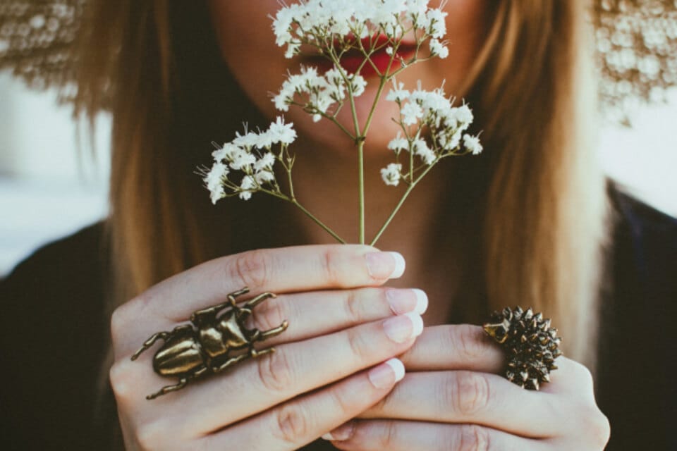 A woman holding flowers with a diamond engagement ring on her hand