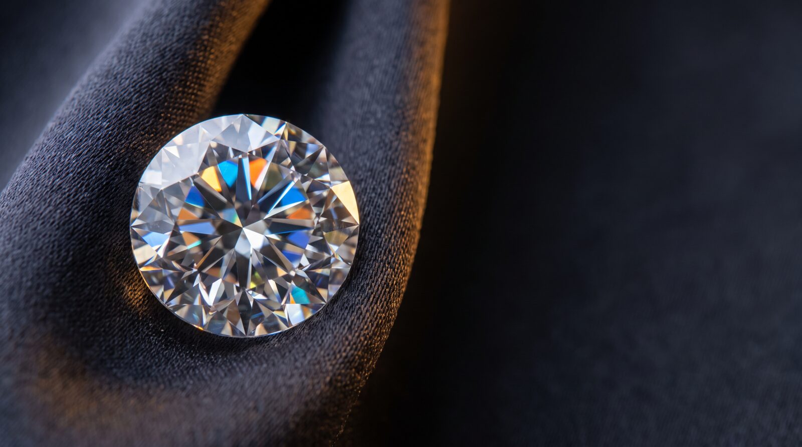 A certified natural round brilliant diamond catching the light on dark silk